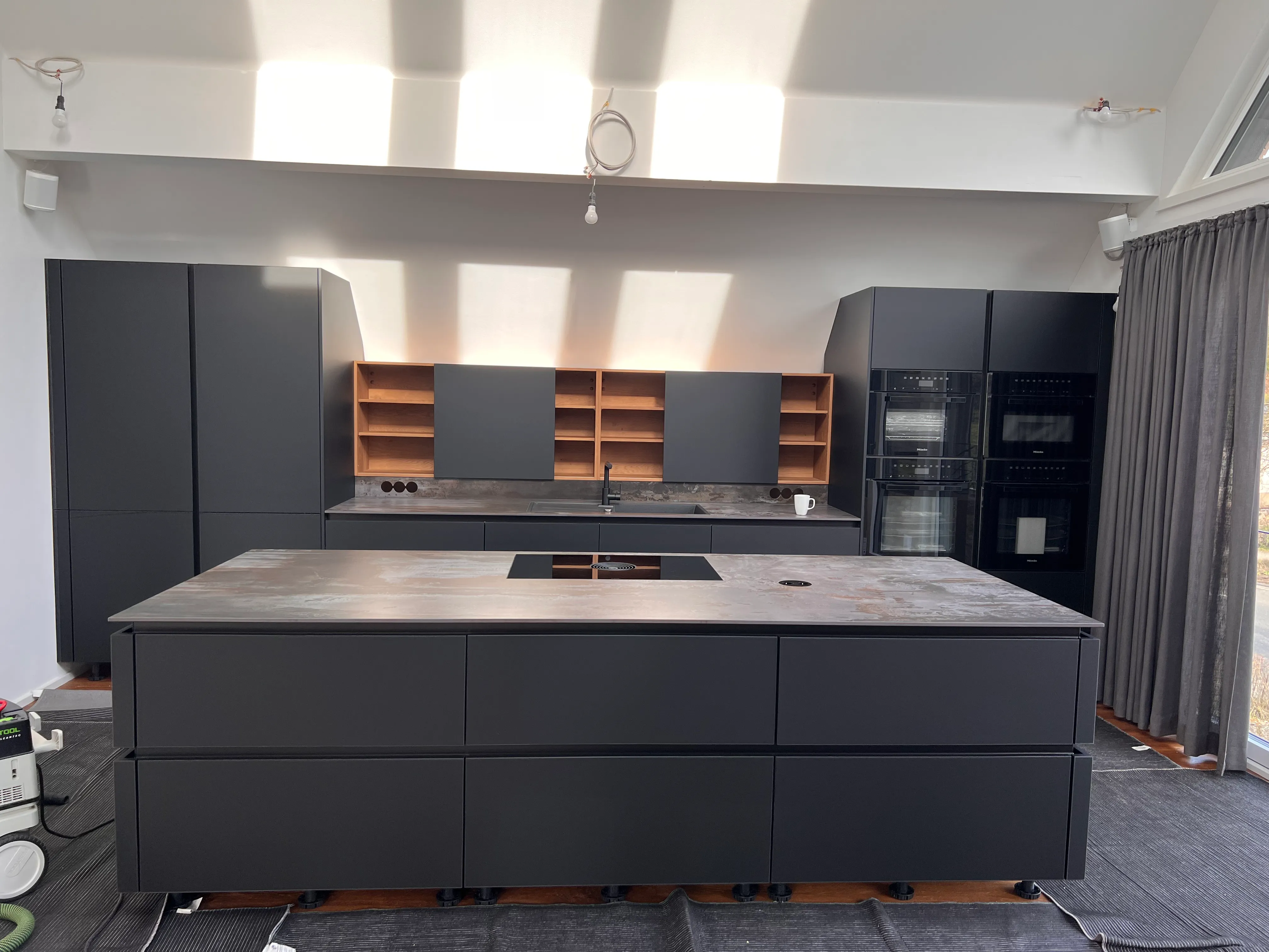 Graue Küche mit großer Kochinsel und warmen Holzregalen