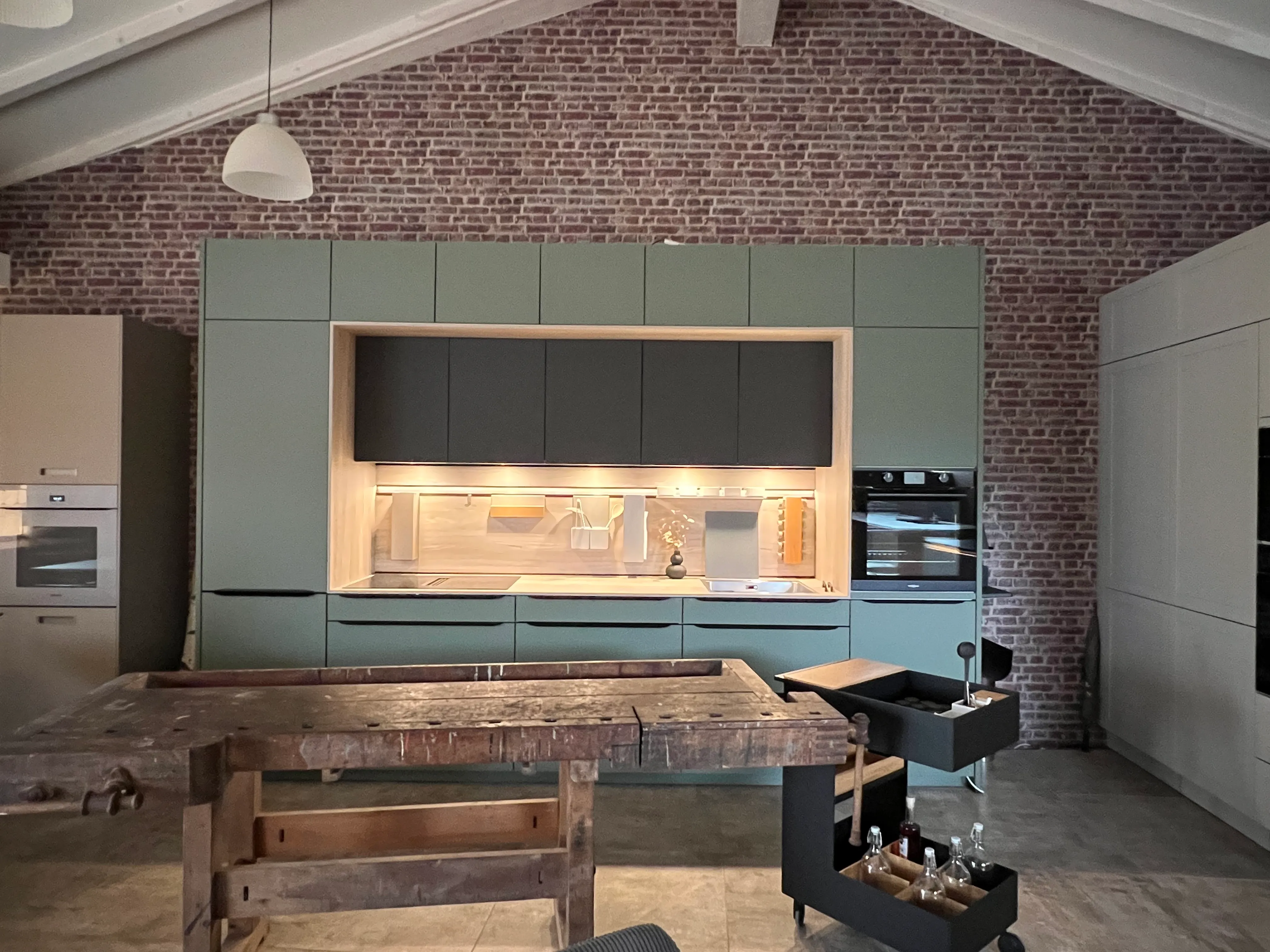 Grüne Musterküche mit offener Nische, Beleuchtung und alter Werkbank