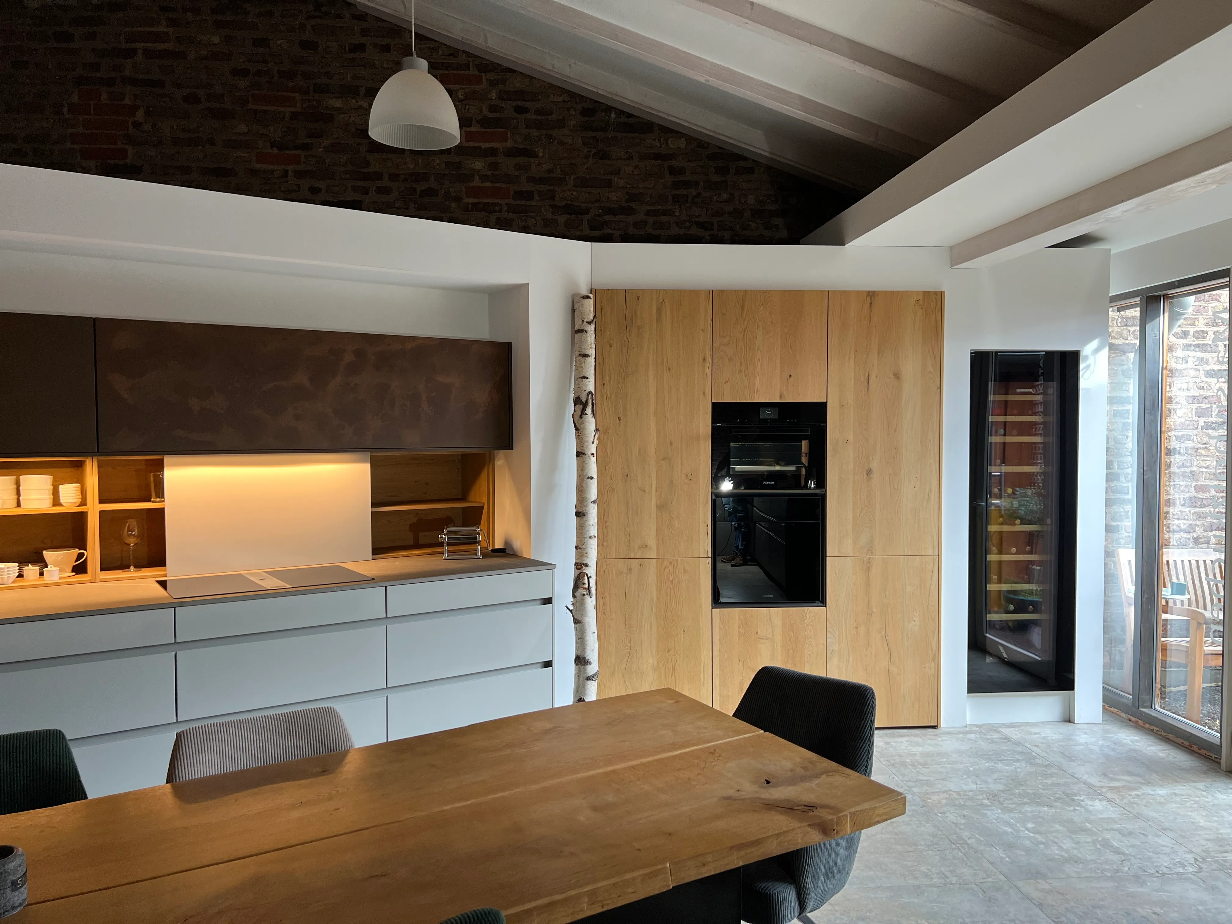 Ausstellungsküche in Grau-Weiß mit Holz-Hochschrank und Weinkühlschrank